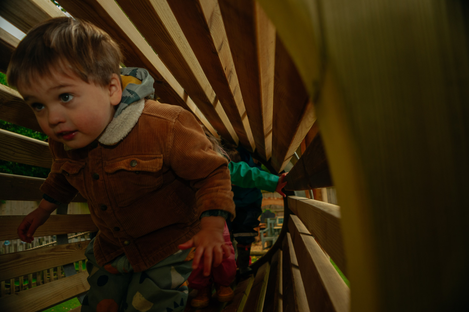 A child exploring inside the wooden play structure