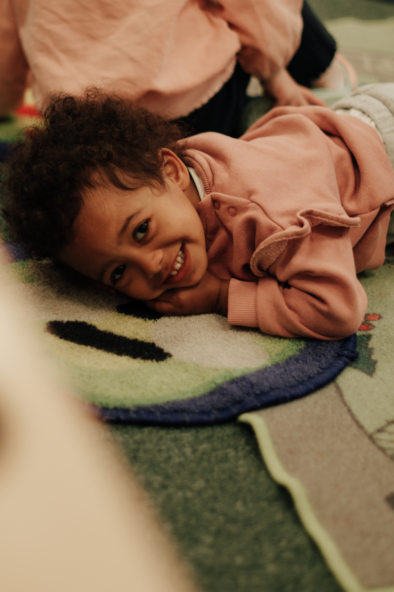 A child smiling on the nursery play rug