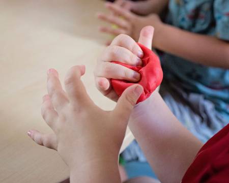 Small hands shaping red playdough together